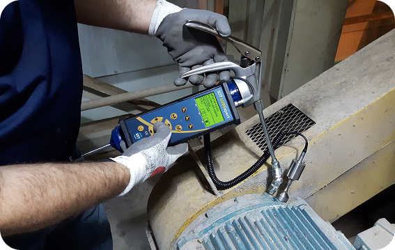Worker applying lubricant to an electric motor bearing while monitoring ultrasonic feedback with an SDT LUBExpert.