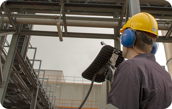 Maintenance technician using SonaVu acoustic camera to detect pressurized air leaks in a noisy industrial environment.